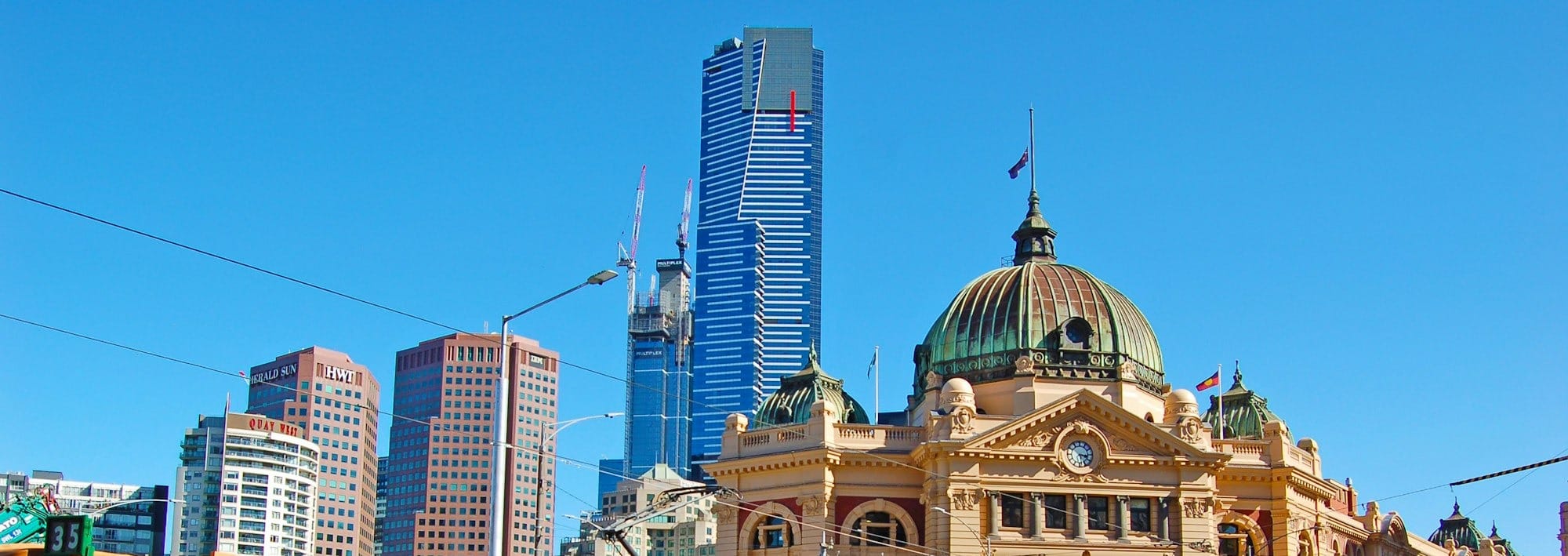 ایک سبز اور پیلی ٹرین ایک اونچی عمارت کے پاس سے گزر رہی ہے