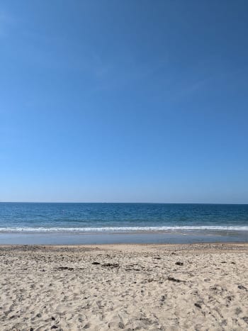 A photo of an empty beach. The sky and water are very blue. It's a calm day.