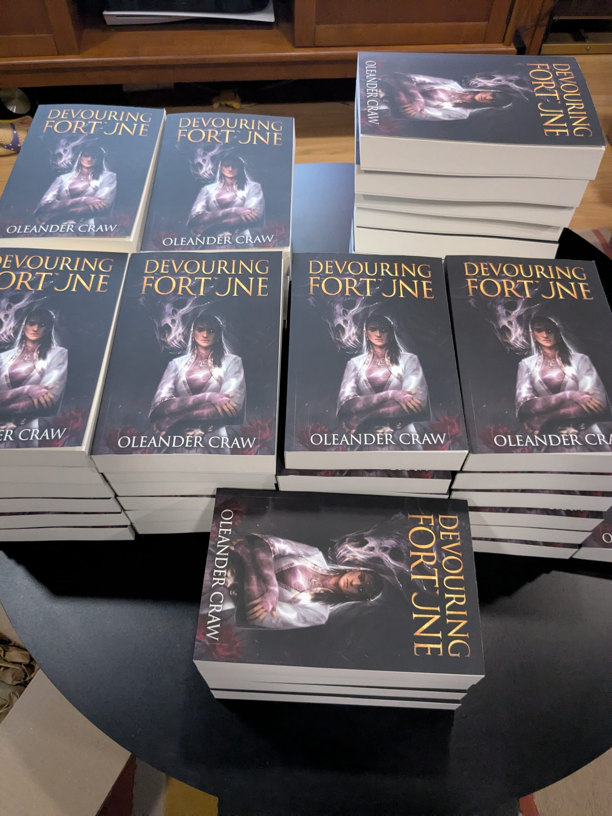 A stack of Devouring Fortune books on a coffee table