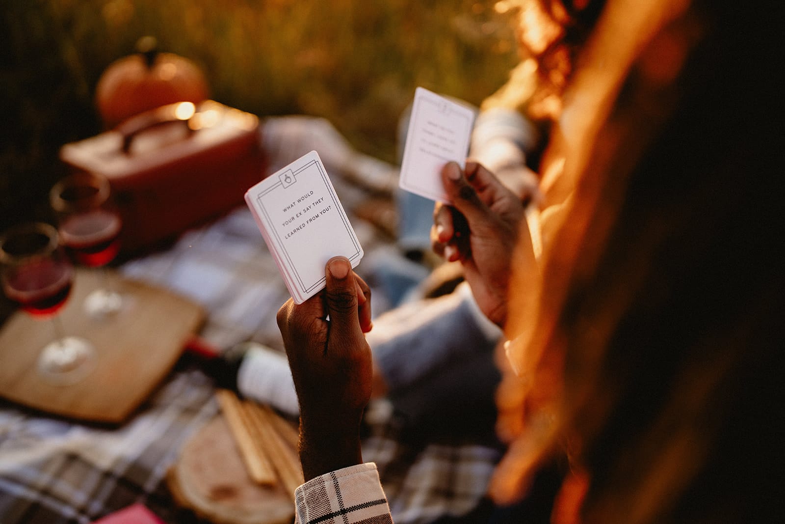 Couple in a picnic drinking wine and playing a card game about questions on relationships