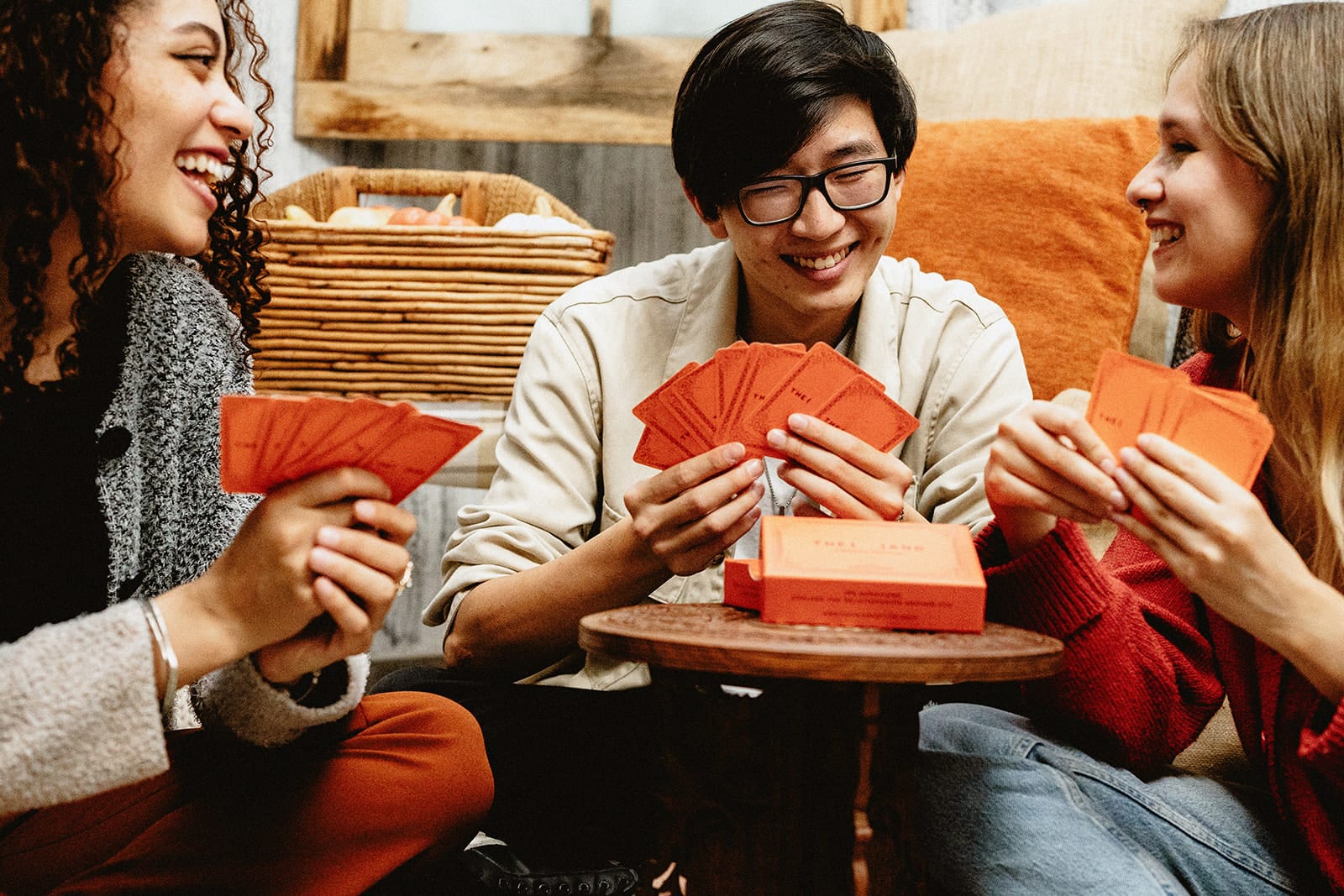 Three people playing a card game and laughing