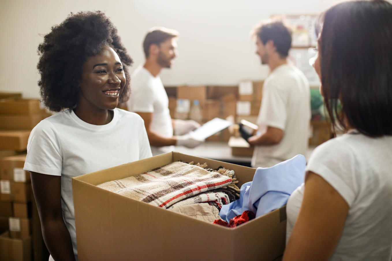 A woman gives a box of donated items to another woman