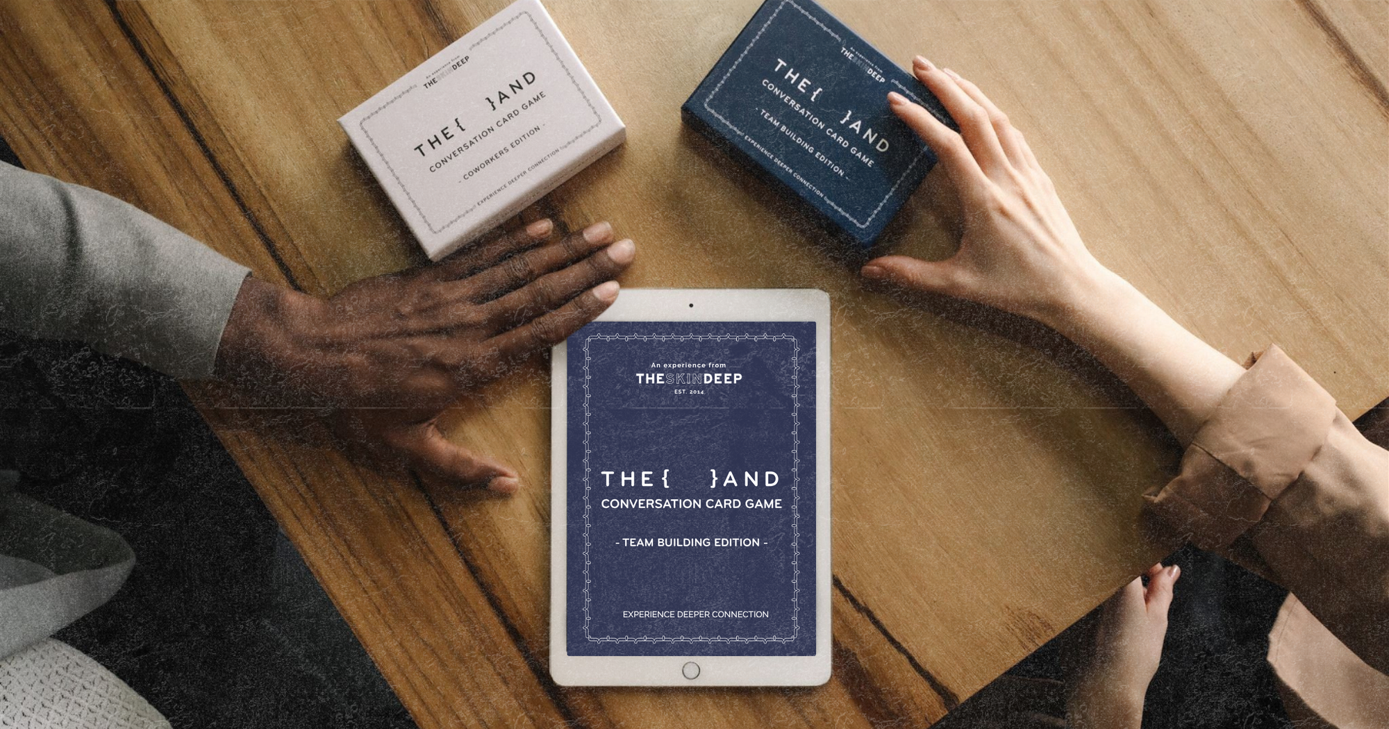 Two hands touching card games and an iPad on a wood table about to play a card game