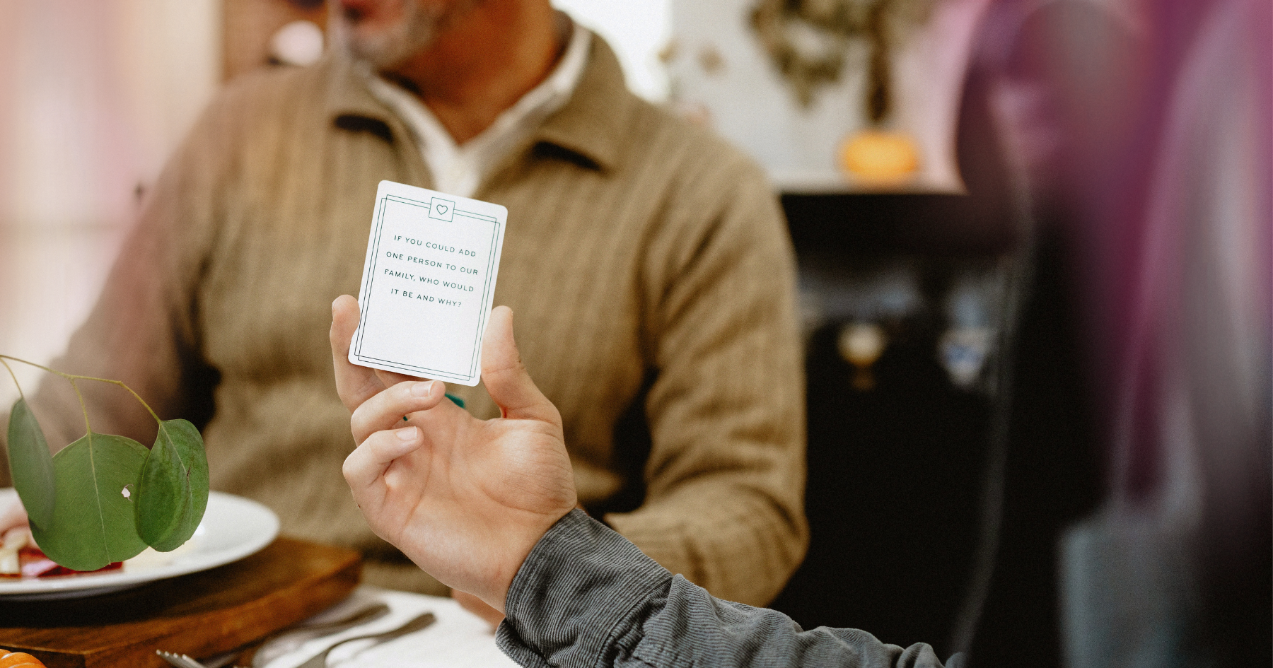 Picture of a hand holding a card and a man behind
