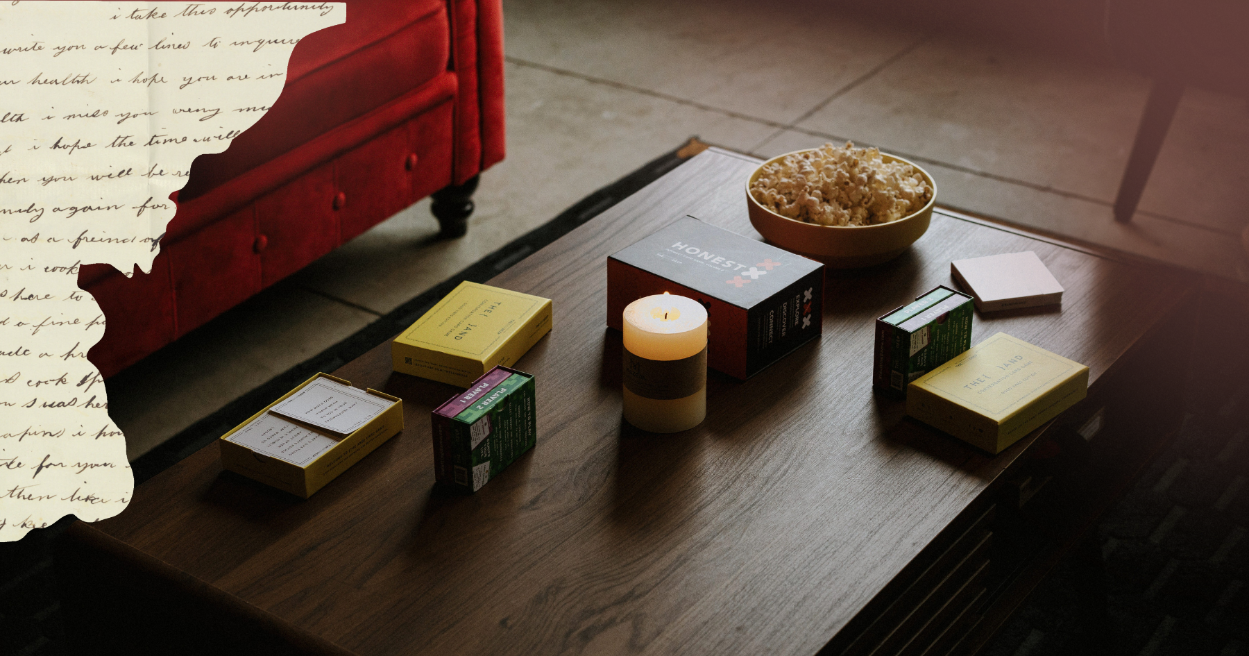 Picture of different card games on a wooden table with a lit candle and a bowl of popcorn