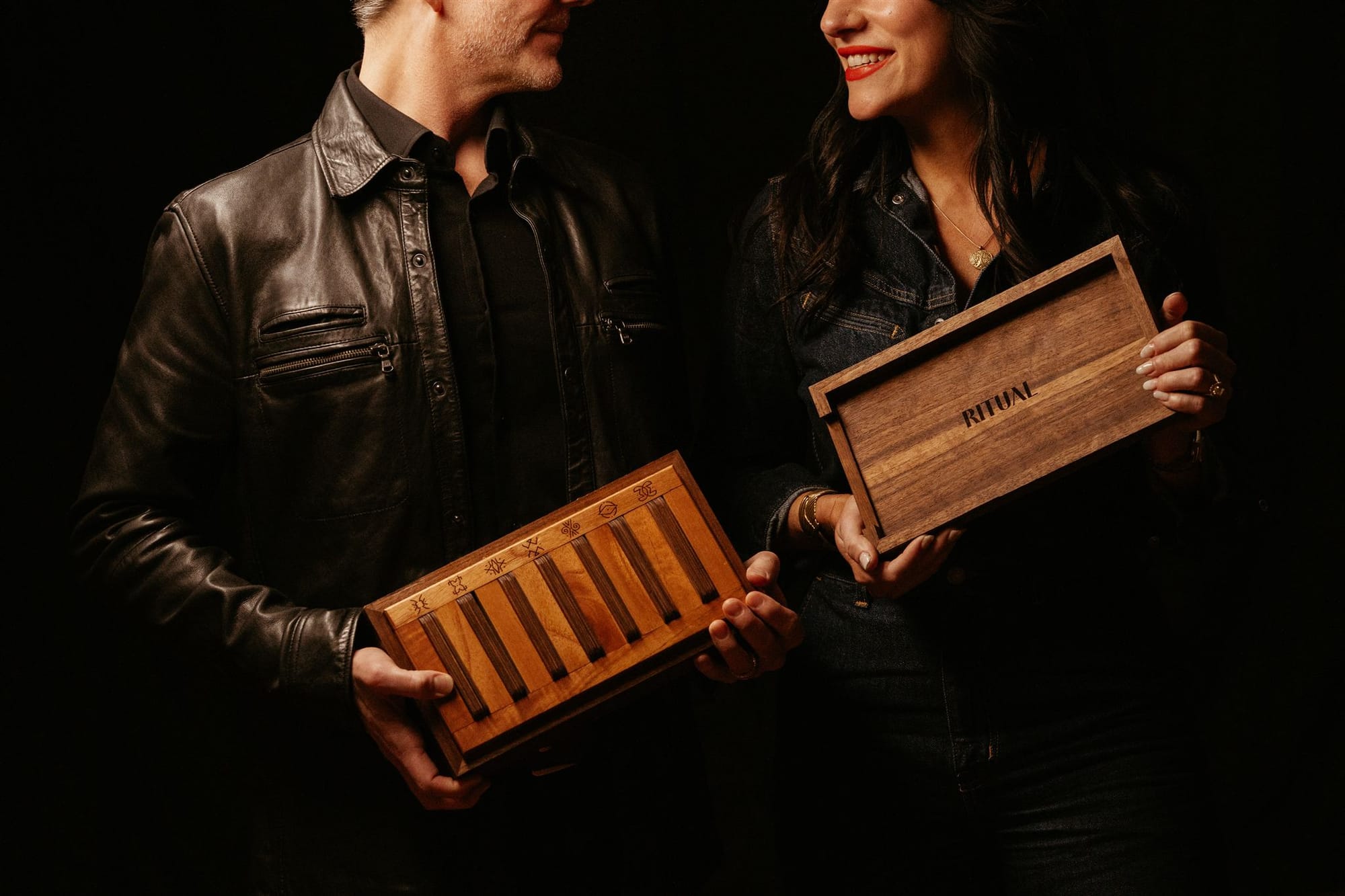 a couple in dark clothes holding a wooden box titled Ritual
