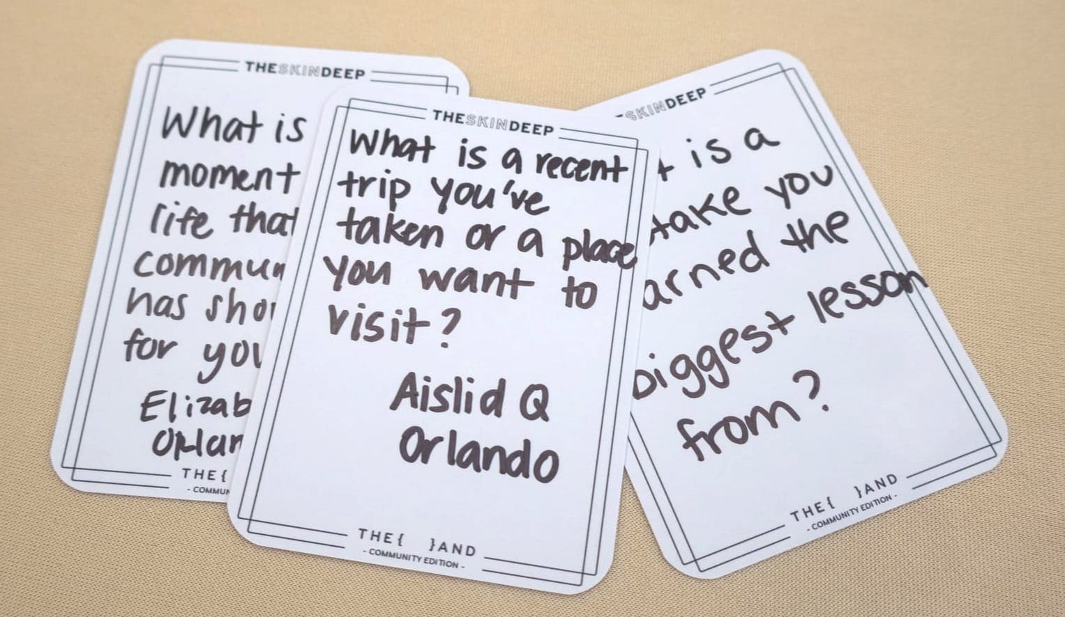 Three handwritten blank cards from The Skin Deep's {THE AND} Community Edition, written by guests at Elizabeth's Orlando gathering, including questions about community, travel, and life lessons.