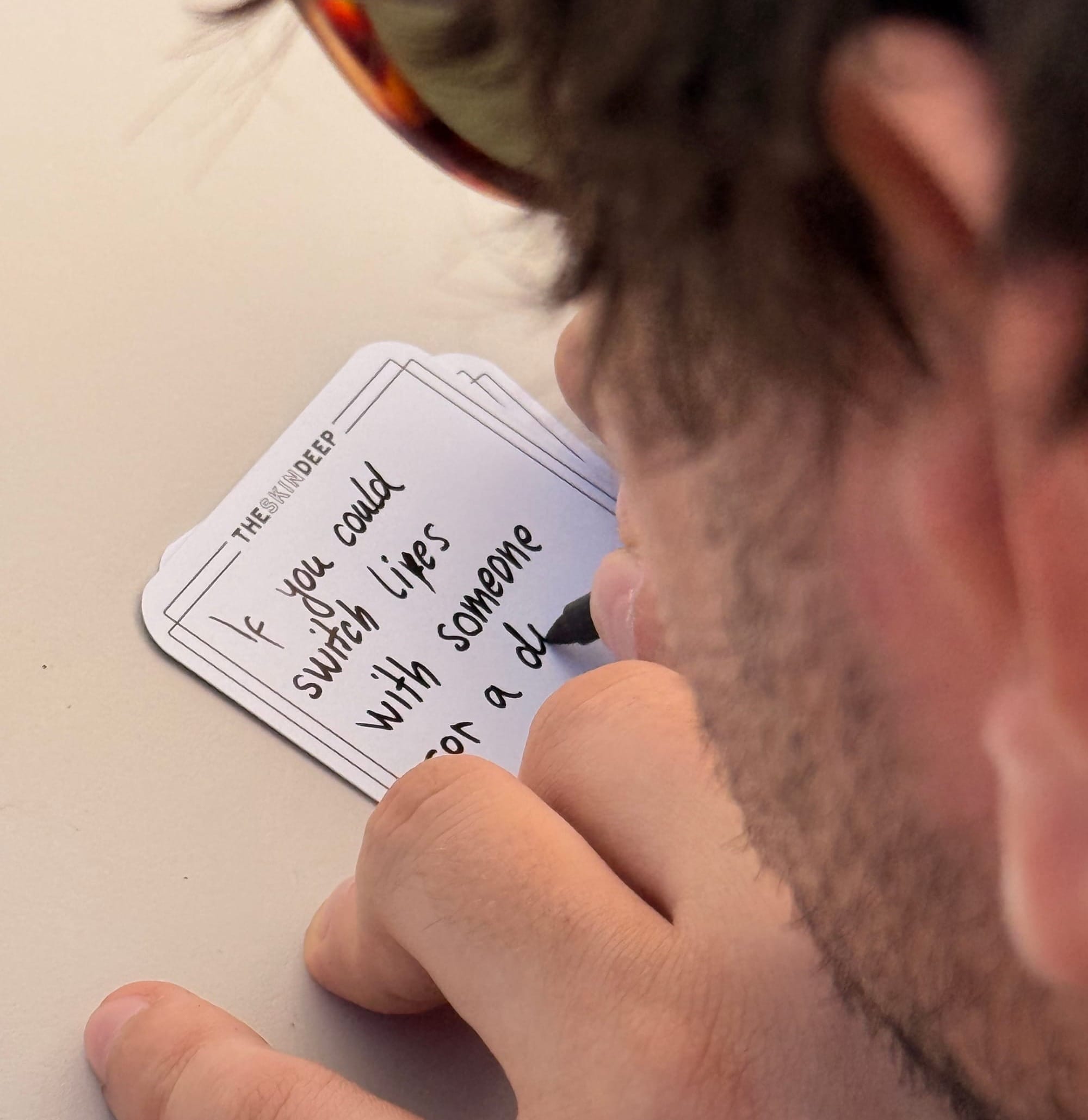 Close-up of a guest at Angie's Croatia gathering handwriting a question on a blank {THE AND} card: "If you could switch lives with someone for a day..."