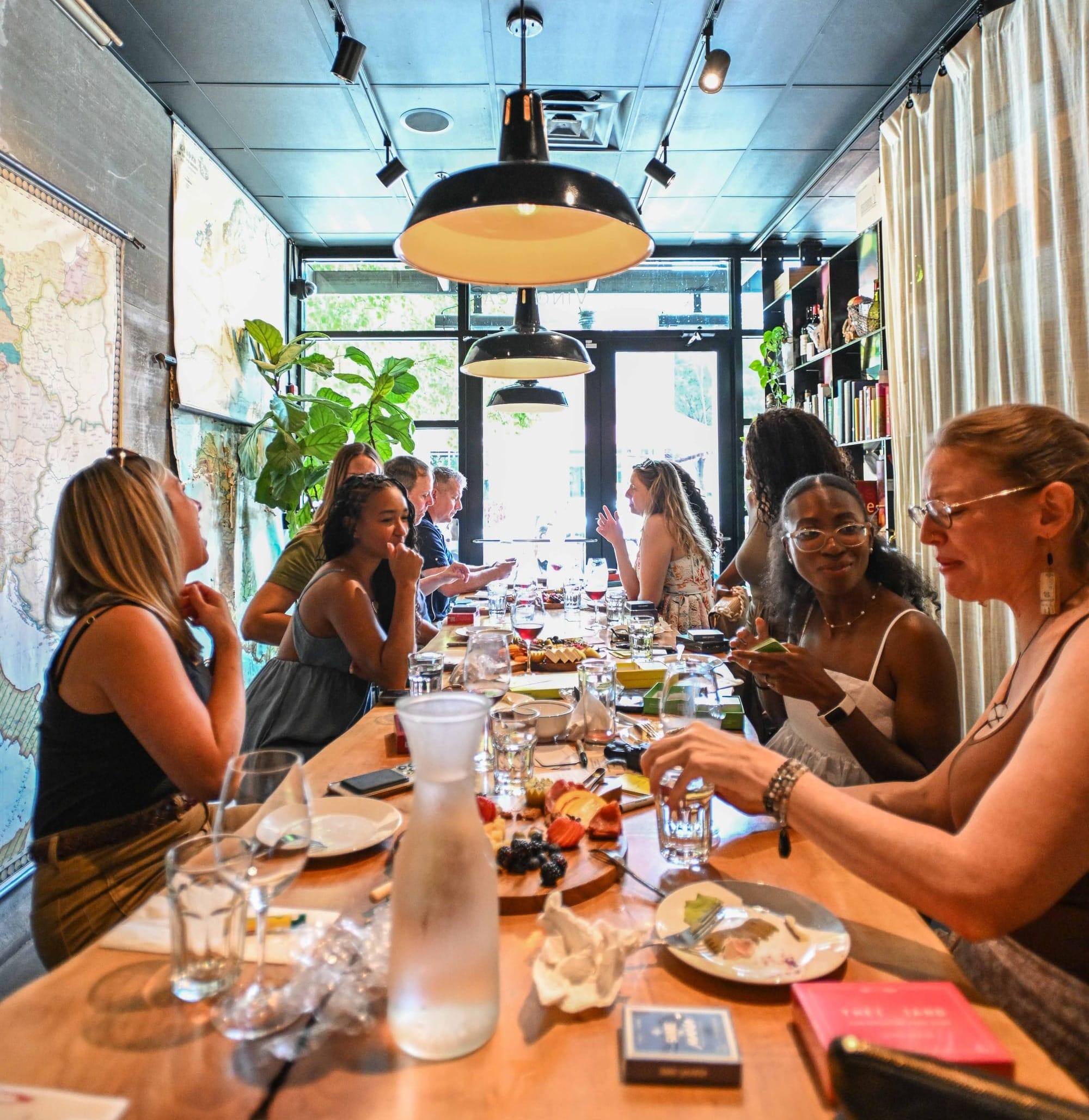 A long table of guests at VinoTeca in Atlanta, gathered for Lenna's Community Celebration event with wine, charcuterie, and {THE AND} cards.