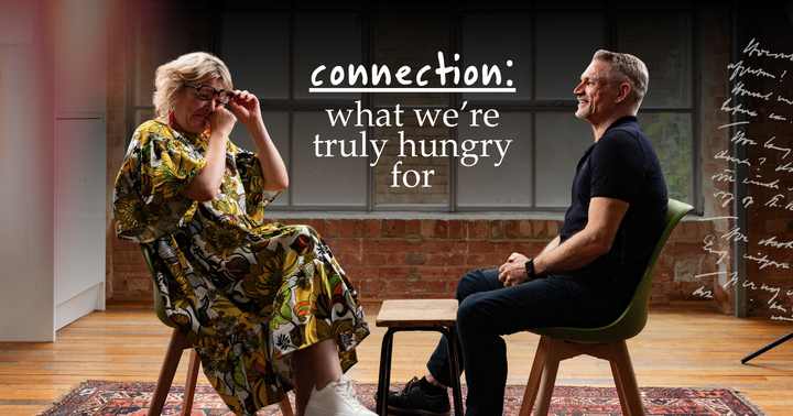 Picture of a man and woman sitting face to face, smiling and crying having a conversation.