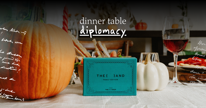 Picture of a card game for families on a thanksgiving table with a glass of wine, bread and pumpkins