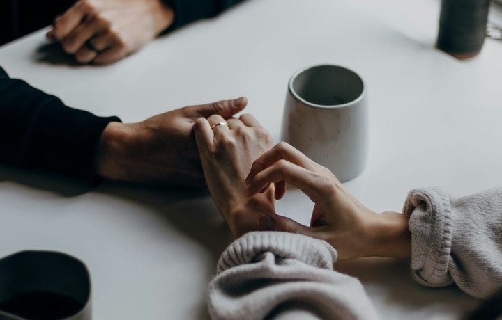 A couple sharing a coffee together with hands touching. 