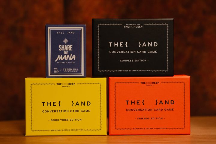 Four {THE AND} card game boxes stacked together: Good Vibes, Friends, Couples, and Share the Mana editions.