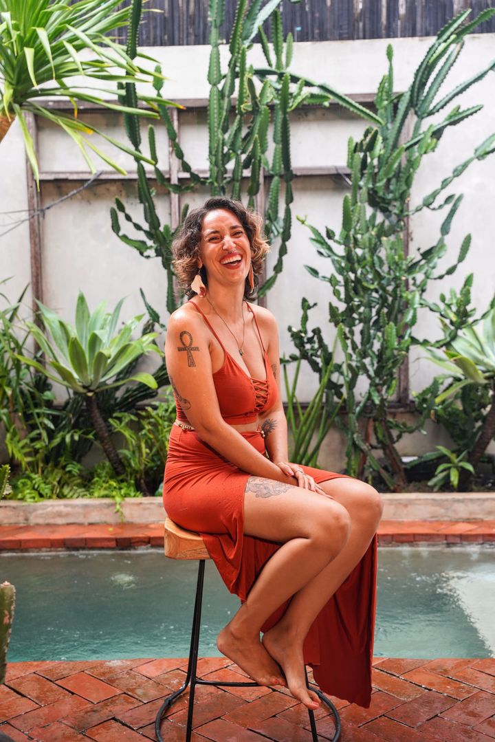 Gianna Shamone laughing while seated poolside, surrounded by cacti and greenery.