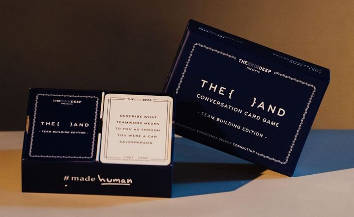 {THE AND} Team Building Edition box open, showing a card about describing teamwork as a car salesperson.