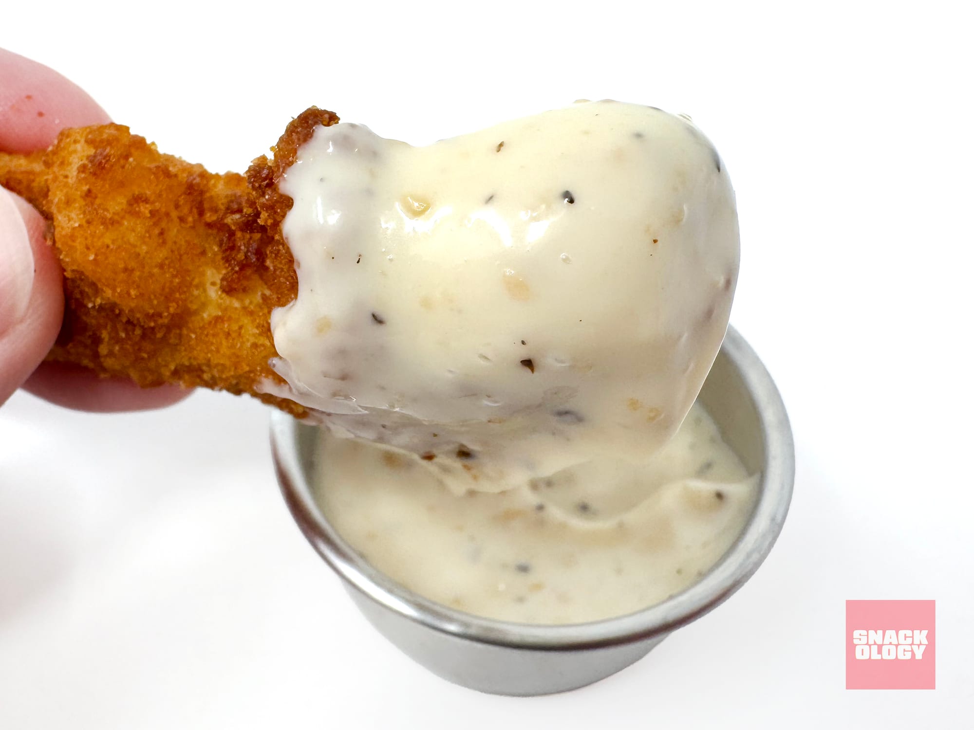 A dino nugget dipped in Heinz Lemon Pepper Parm Mayonnaise-Style Dip. / Snackology