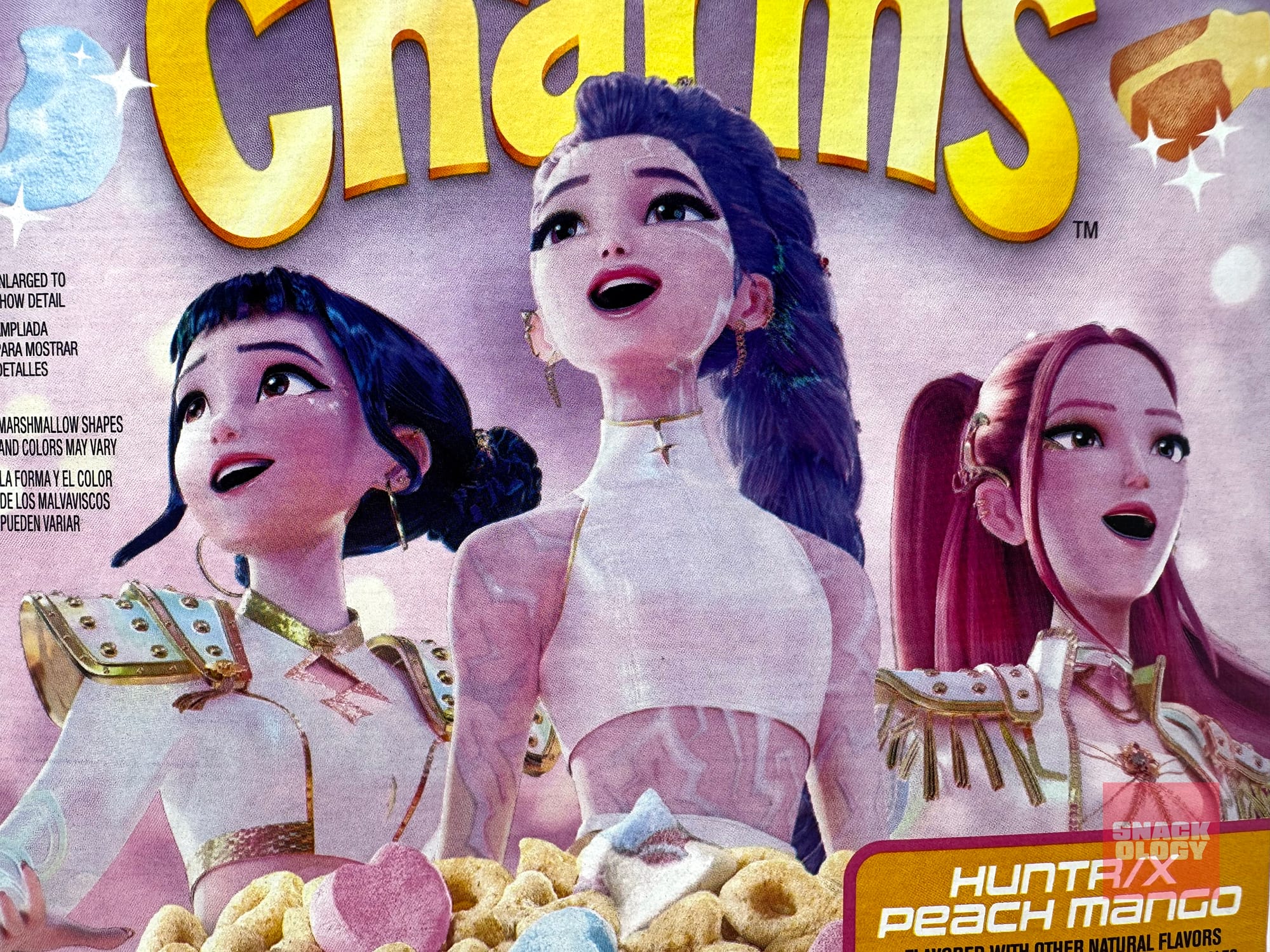 Zoey, Rumi and Mira on the box of HUNTR/X Peach Mango Lucky Charms
