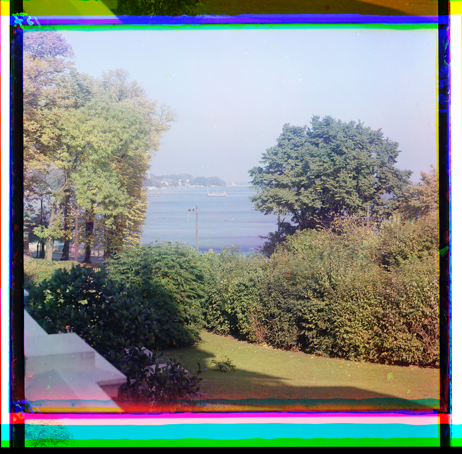 Color photograph, the grounds of Hvidøre green in front with the sea behind with a ship visible.