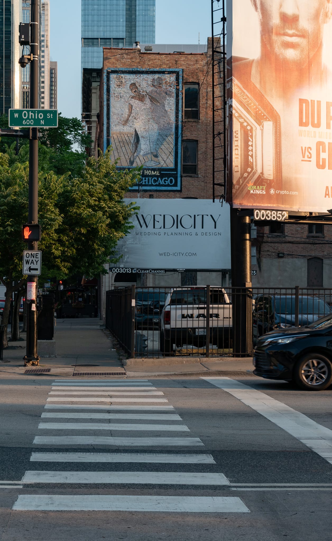 Crosswalk facing a parking lot, ads on the side of a building