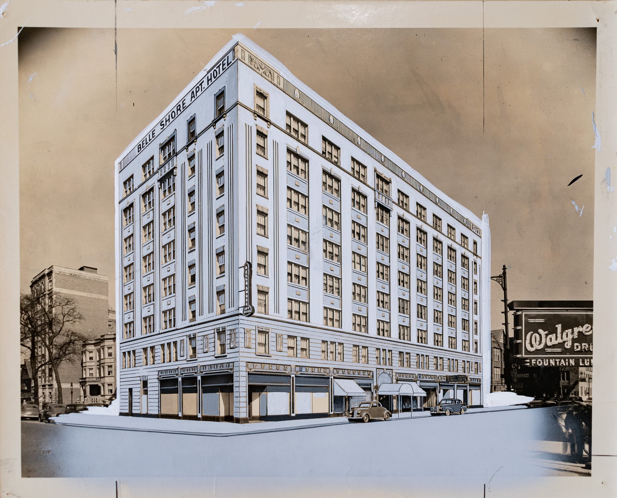 Photo with grey painted retouching of the Belle Shore Apartment Hotel, an eight story building on a corner with two cars parked in front, a Walgreens sign sticking out in the foreground.