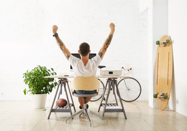 A tattoed freelancer in front of his working space, surrounded with his hobby toys longboard. Showing the innovative pricing 