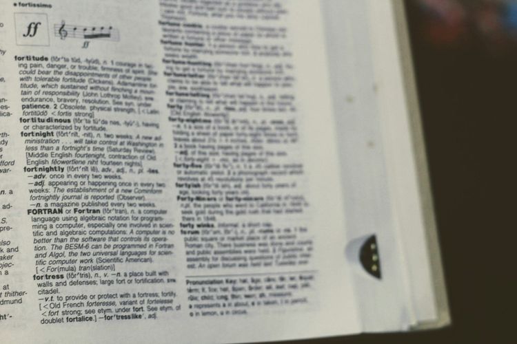 A close-up of a printed reference page showing a FORTRAN entry, representing the idea that precise definitions belong in code and configuration, not in the heads of individual data analysts.