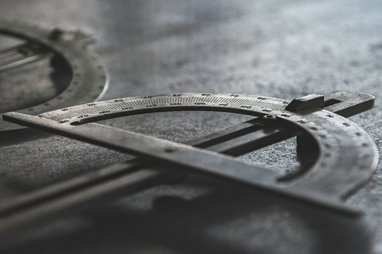 A grayscale close-up of a precision measurement compass in sharp detail, representing the quality thresholds that data platforms run on when they are defined rather than inherited.