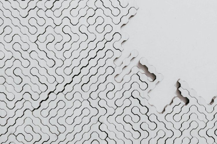 A white interlocking geometric pattern with sections missing from one corner, representing data infrastructure running on defaults where business decisions were never made.