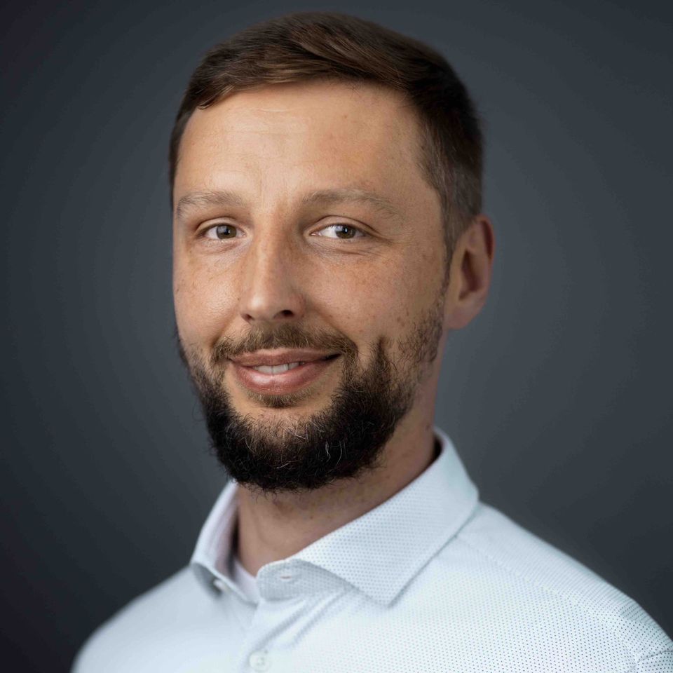 Professional headshot of Krzysztof Słowiński, an independent Fractional CTO specialising in Data and Cloud Engineering, wearing a white shirt against a neutral grey background.