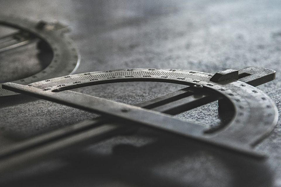 A grayscale close-up of a precision measurement compass in sharp detail, representing the quality thresholds that data platforms run on when they are defined rather than inherited.
