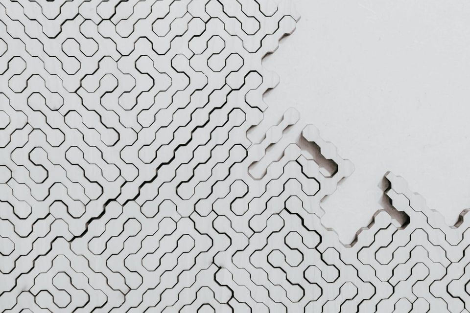 A white interlocking geometric pattern with sections missing from one corner, representing data infrastructure running on defaults where business decisions were never made.