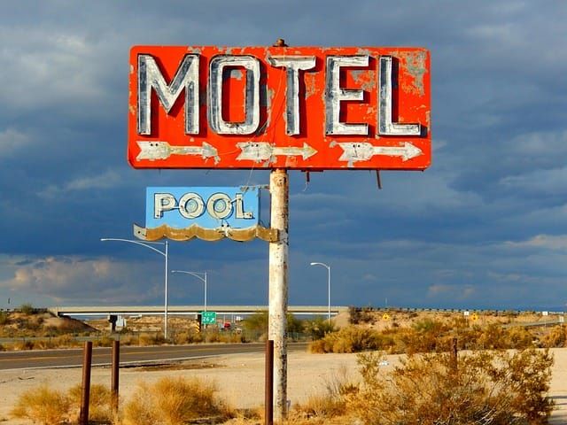 Weather-worn red motel sign on the side of tthe interstate