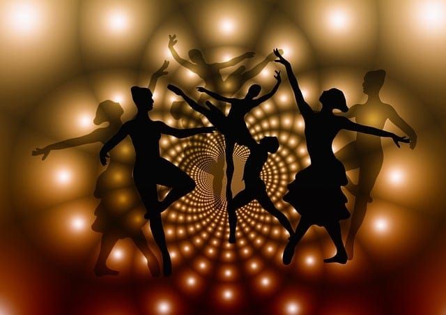 Silhouettes of seven male and female dancers in various dance poses before a dark background with small bright lights