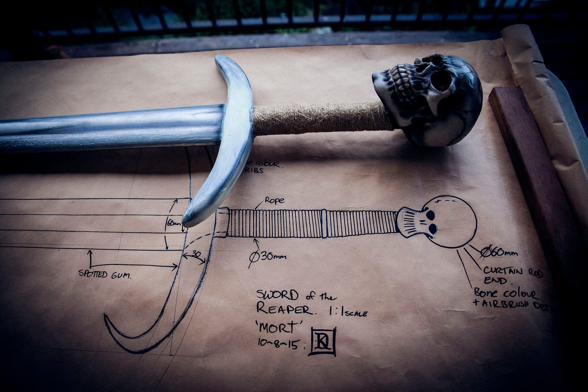 comparing the finished sword to the original design plans 