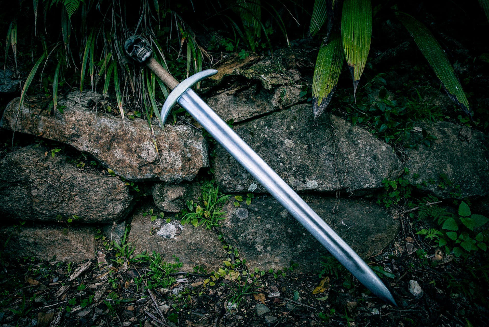 The completed sword in all its glory sitting in the garden against the rock retaining wall