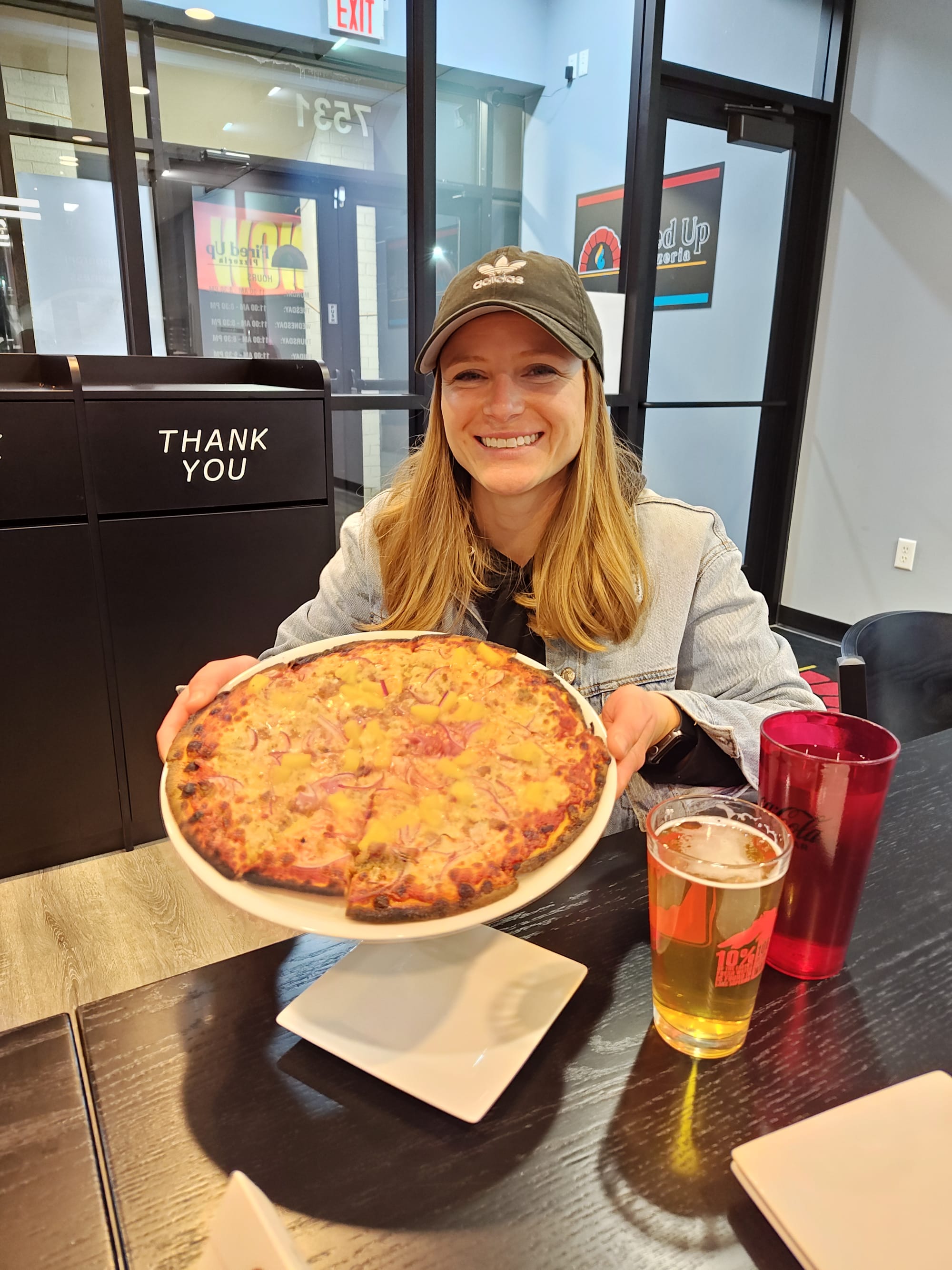 woman smiling and holding an indian pizza