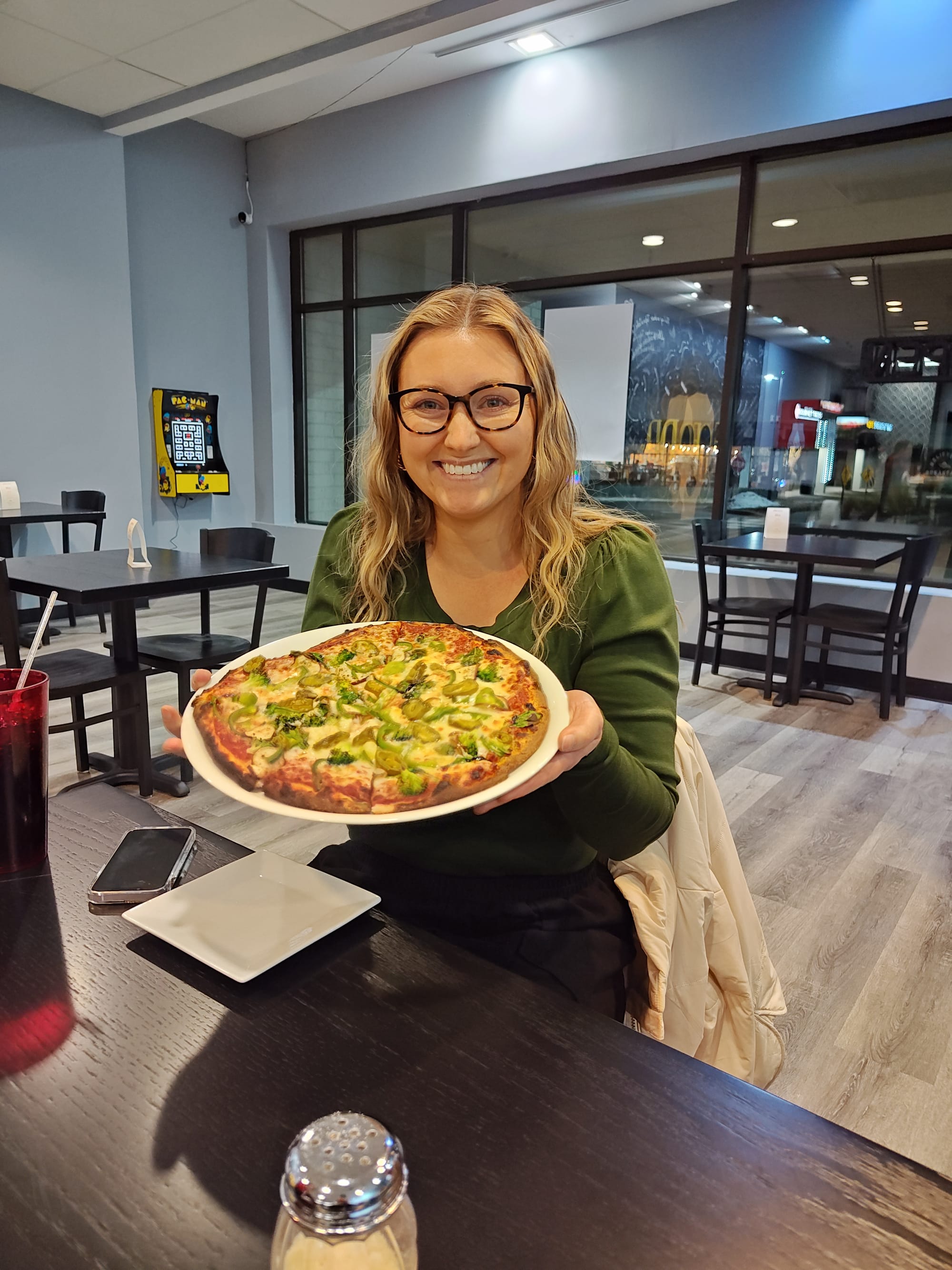 woman smiling and holding a veggie pizza