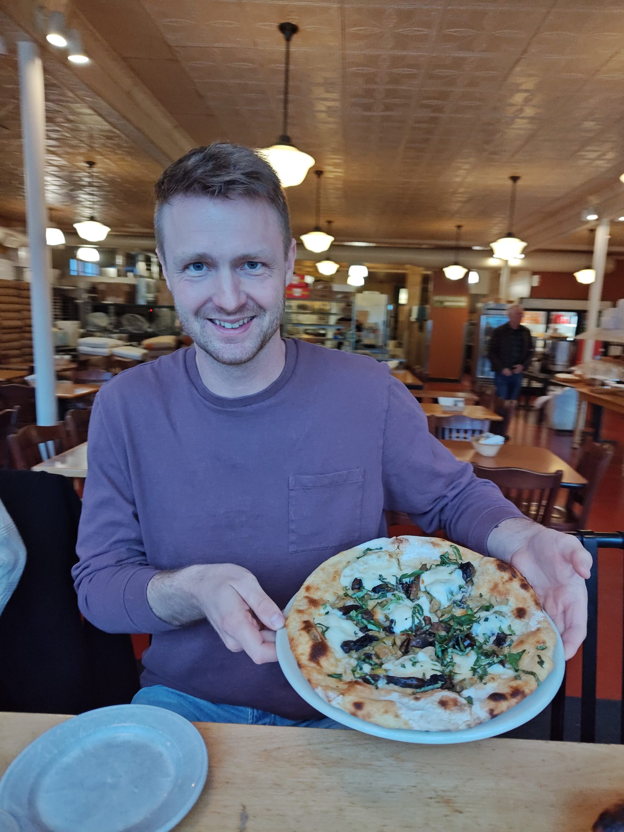 man holding a mushroom and white sauce pizza