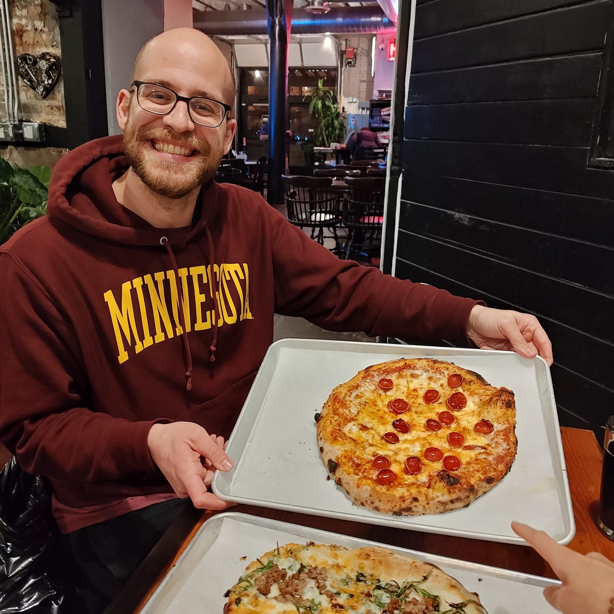 man holding a hot honey pizza