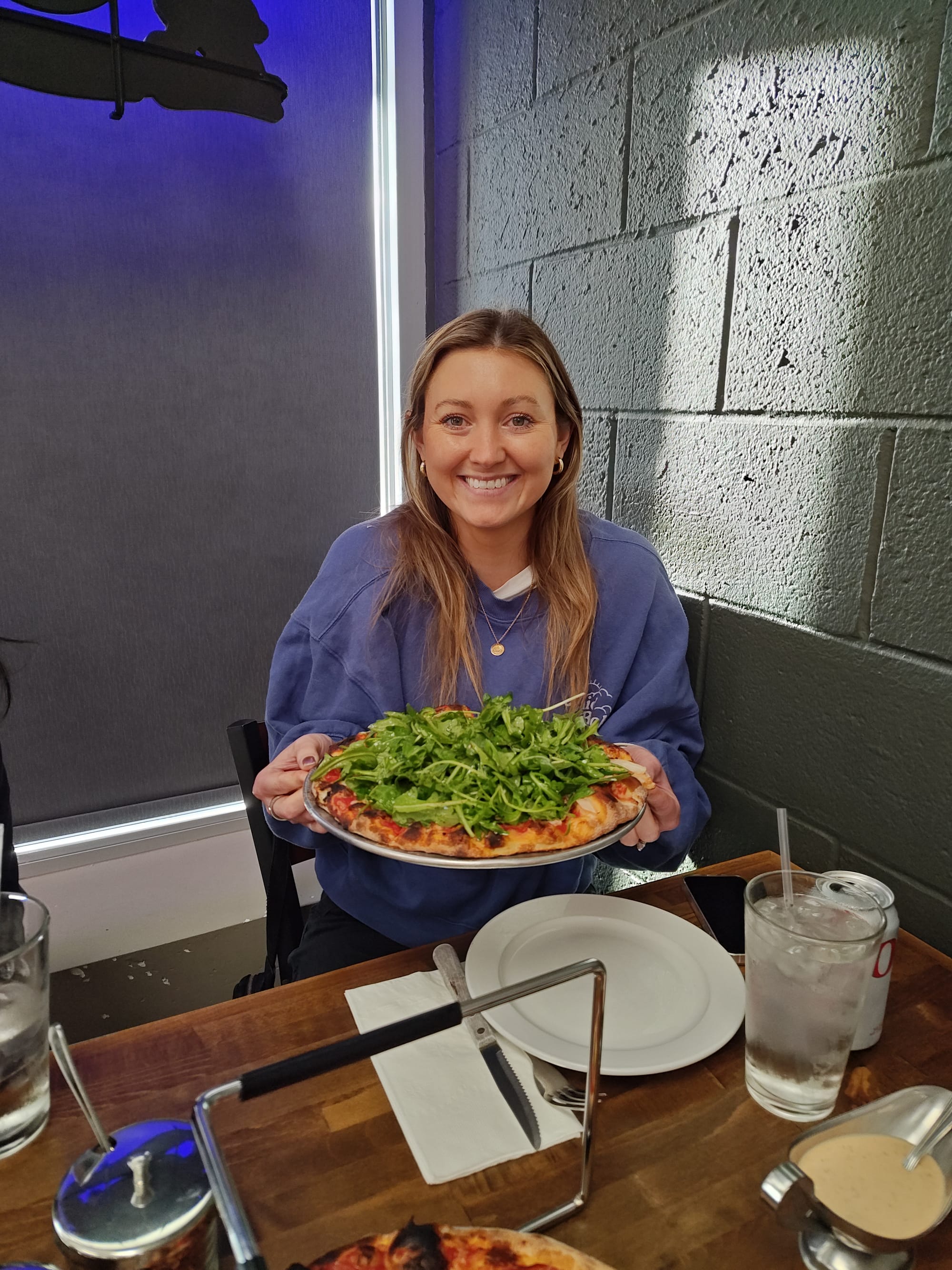 smiling woman holding a chicken pizza