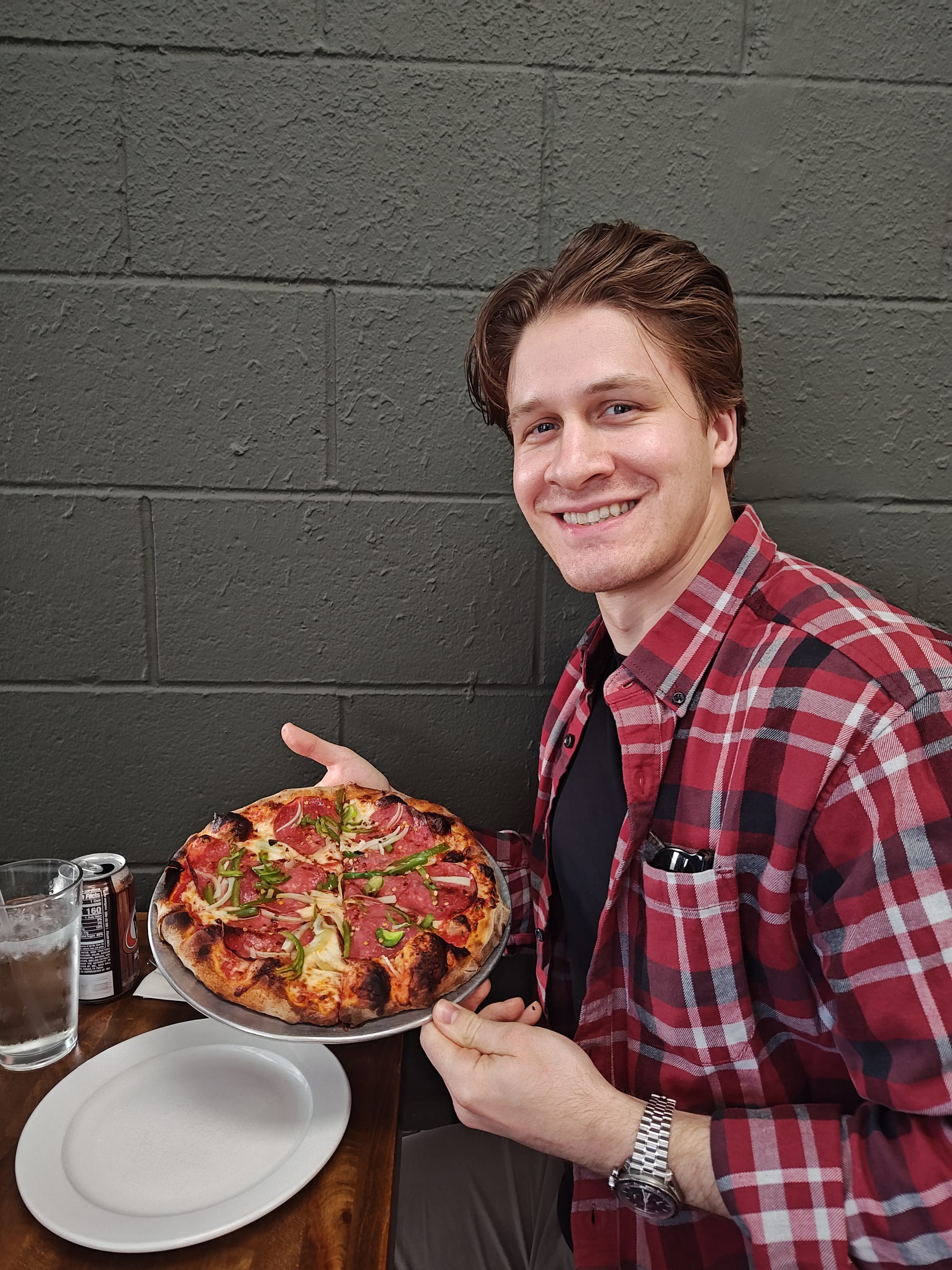 smiling man holding a salami pizza