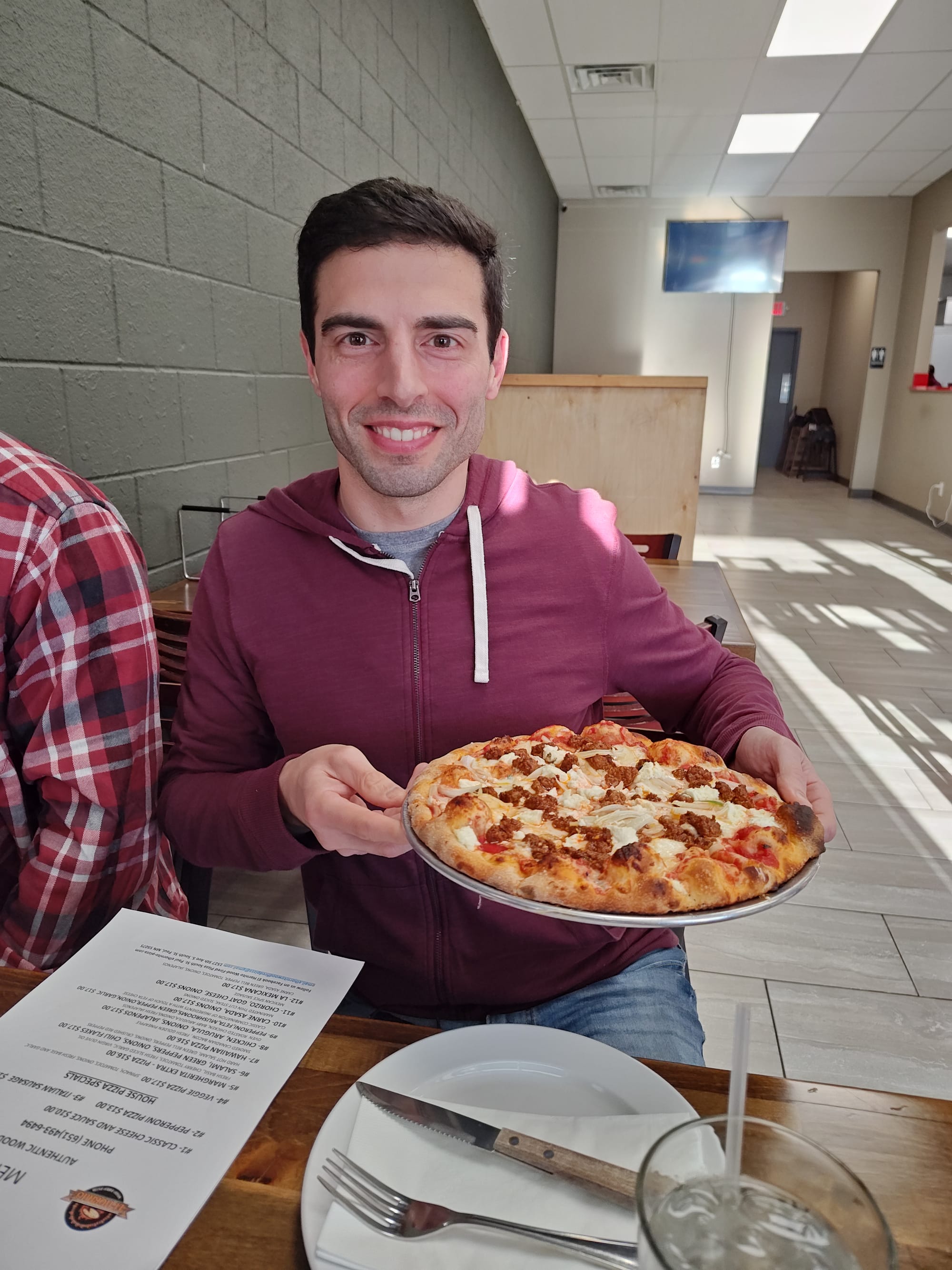 smiling man holding a chorizo pizza