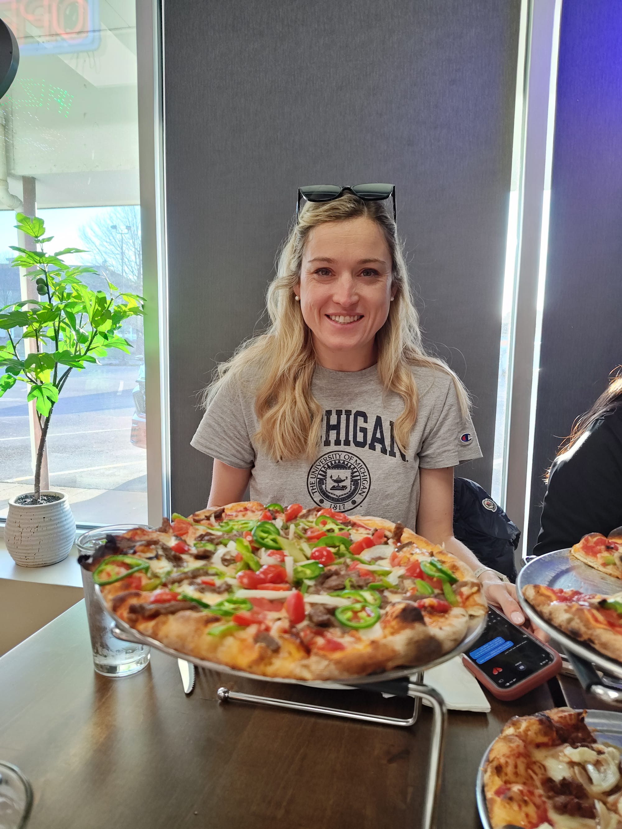 smiling woman behind a mexican flavored pizza