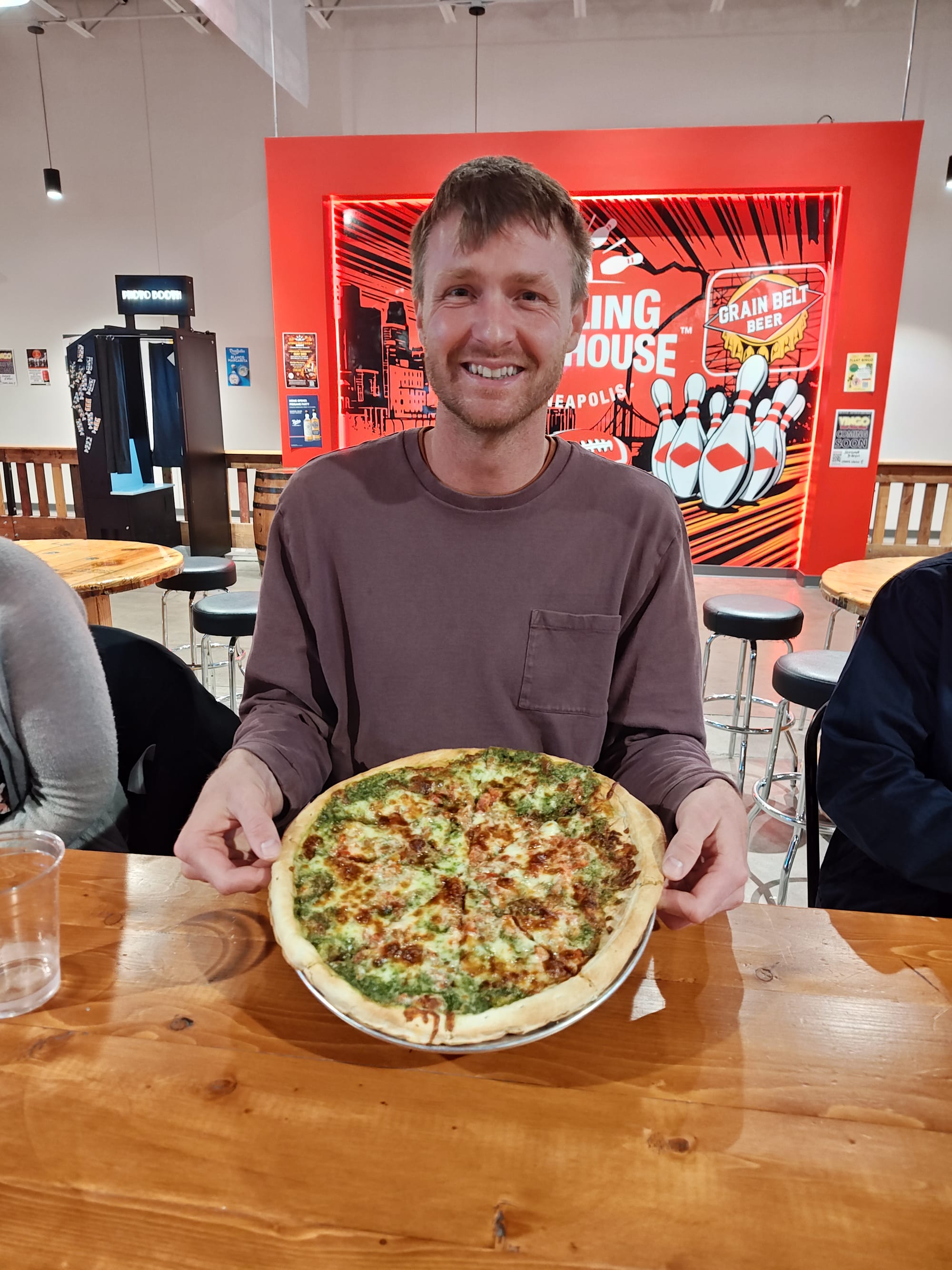 smiling man holding a pesto pizza