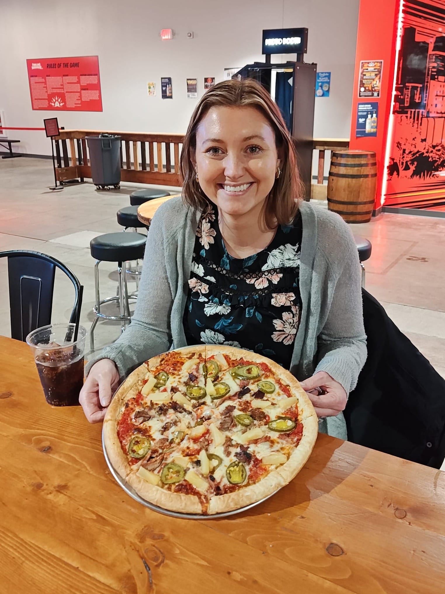 smiling woman holding a pineapple pizza