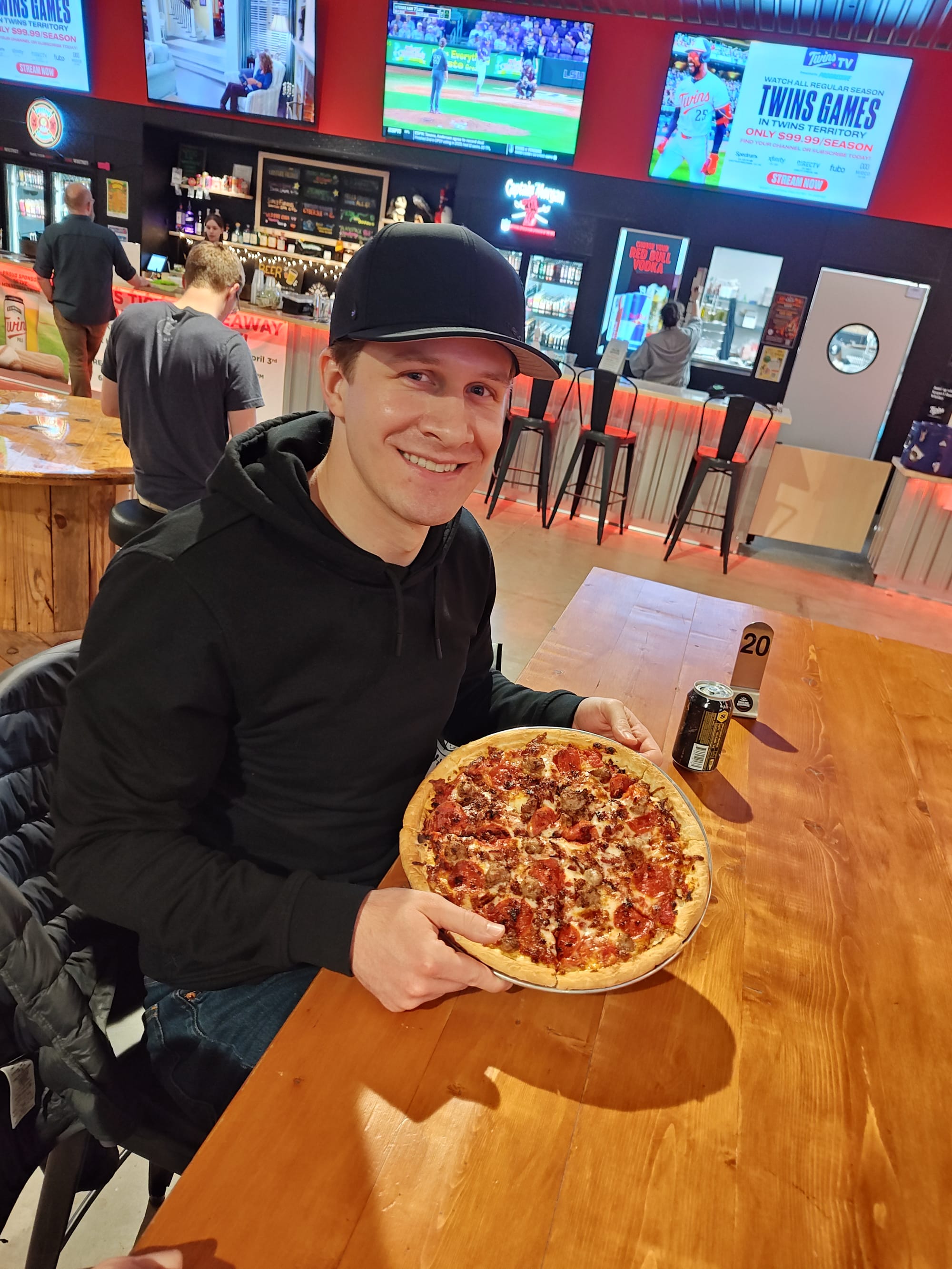 smiling man holding a meat lovers pizza