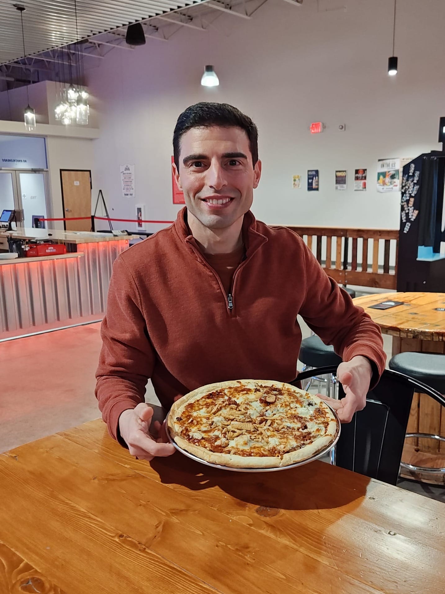 smiling man holding a BBQ chicken pizza