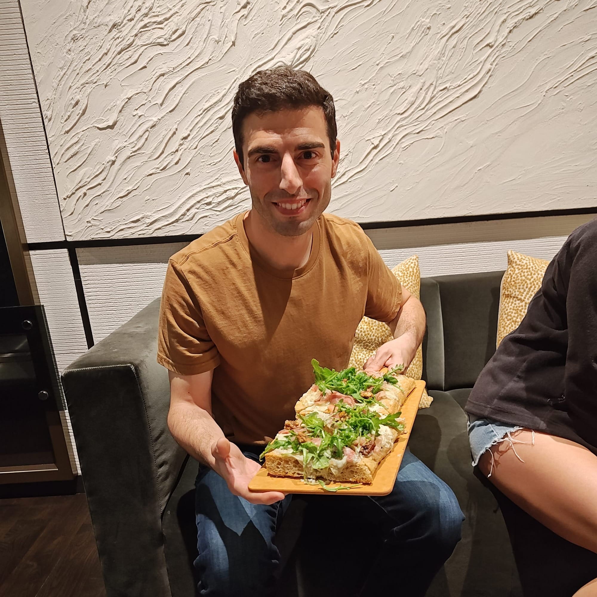 man holding a prosciutto pizza