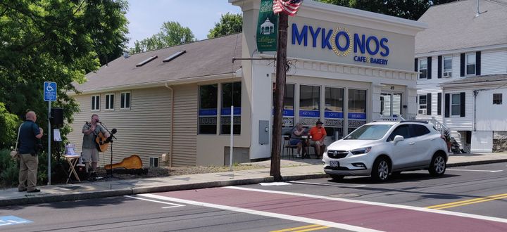 A man playing guitar in front of a restaurant.