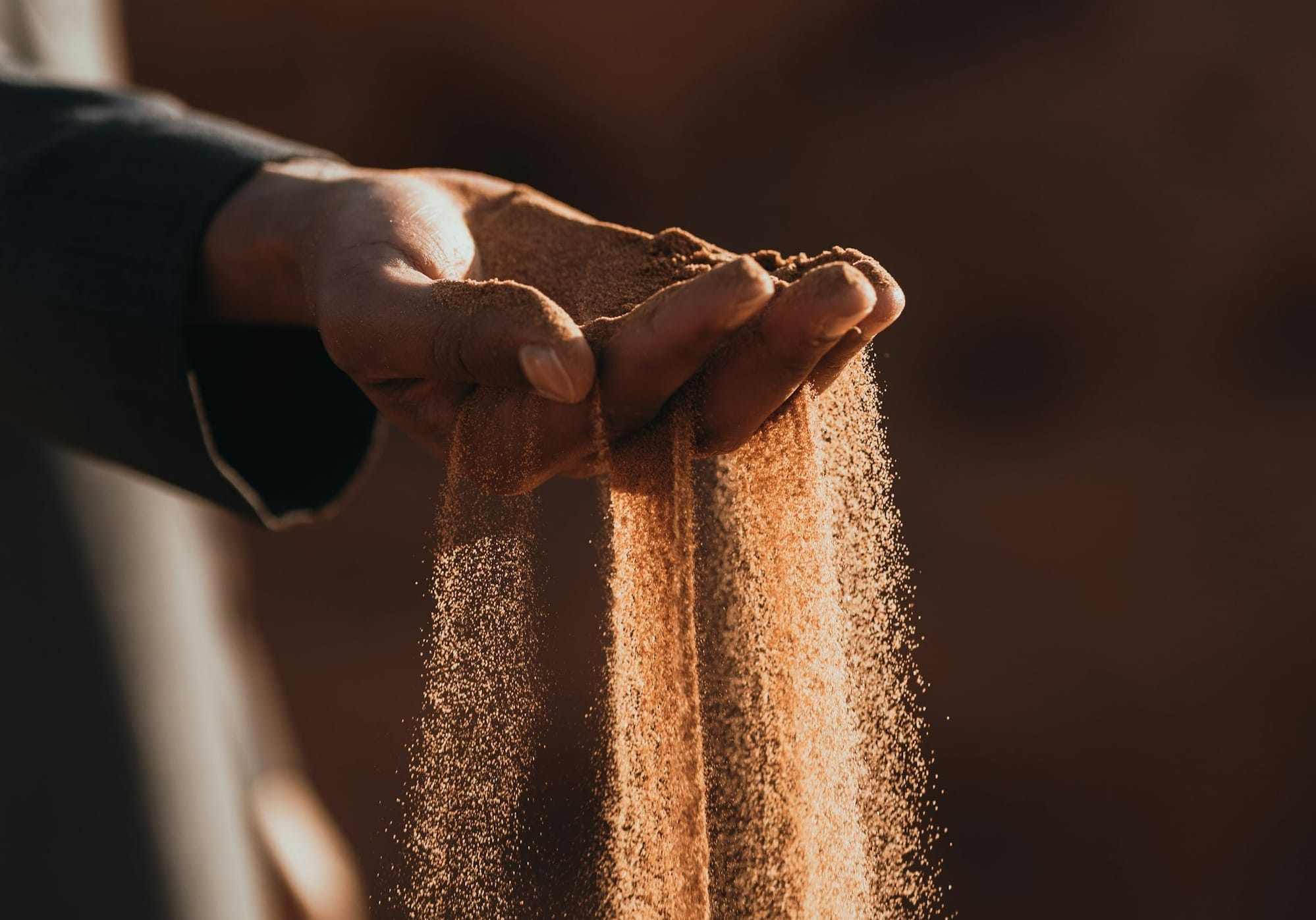 a person holding sand in their hands